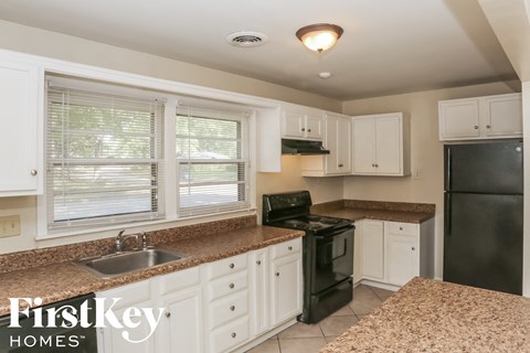 A kitchen with white cabinets and a black refrigerator.