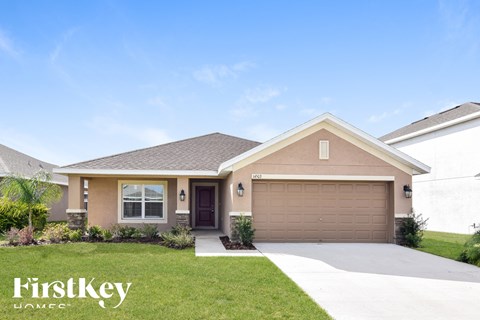 a beige house with a garage door and a lawn
