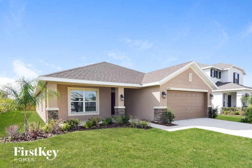 a beige house with a lawn and a driveway