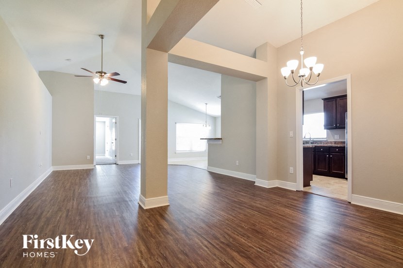 an empty living room with wood floors and a ceiling fan