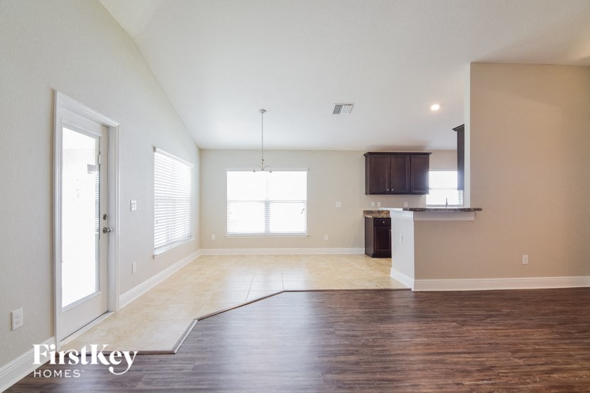 an empty living room with a door to the kitchen