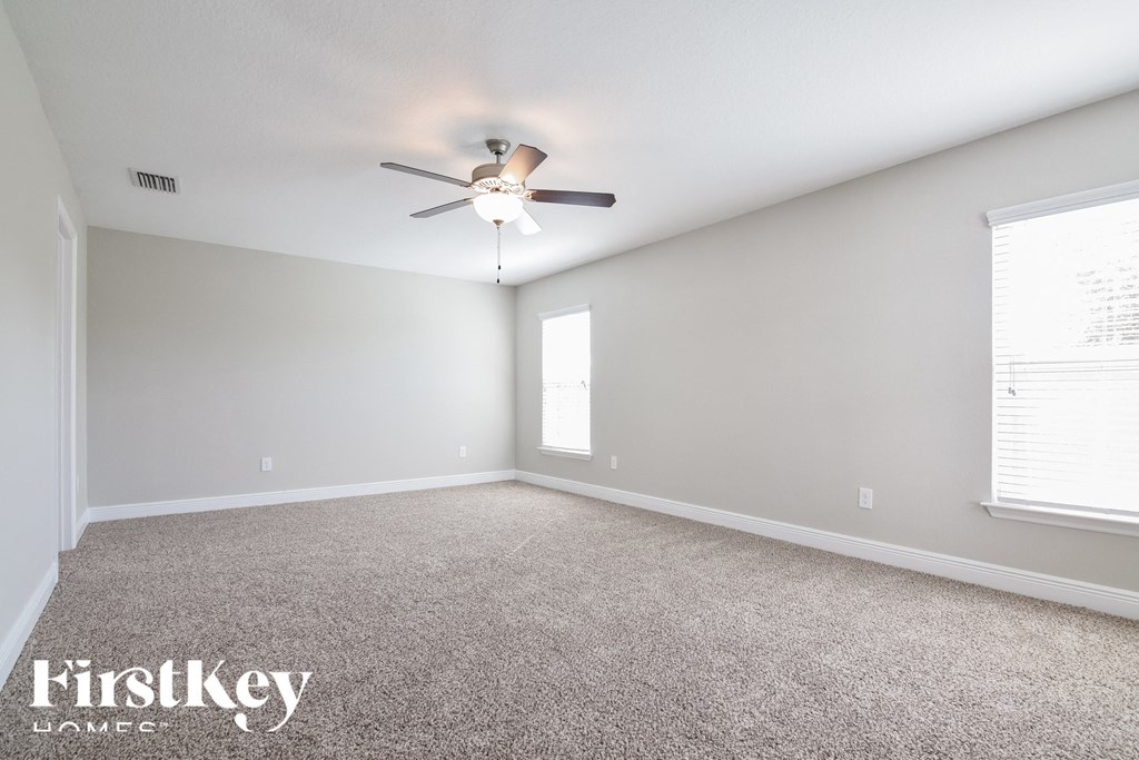 the spacious living room with ceiling fan and carpet