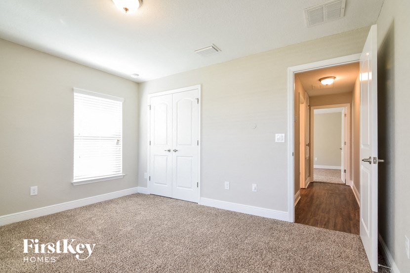an empty living room with a door and a hallway to a bedroom