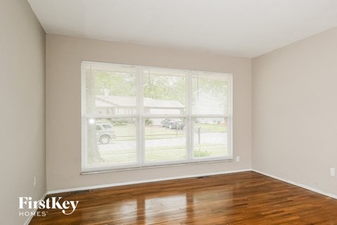the living room of a home with a large window and wood floors