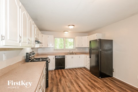 a kitchen with white cabinets and a black refrigerator