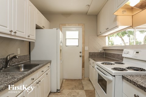 A kitchen with white cabinets and appliances is for sale.