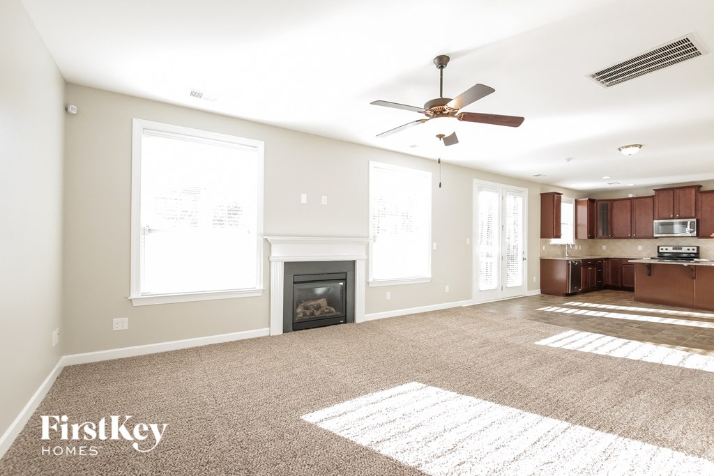 an empty living room with a fireplace and a ceiling fan