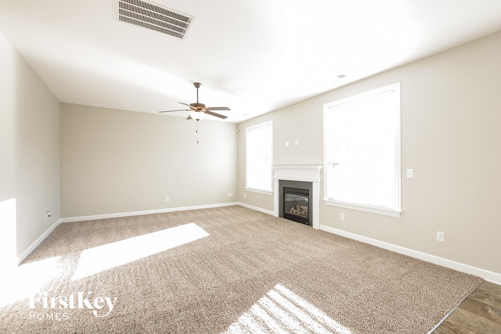 an empty living room with a fireplace and a ceiling fan