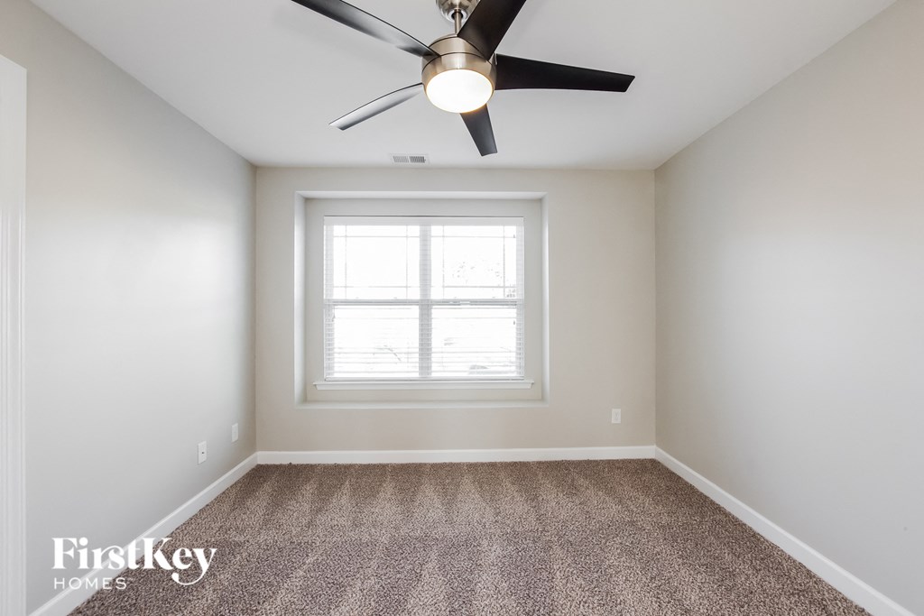 an empty room with a ceiling fan and a window