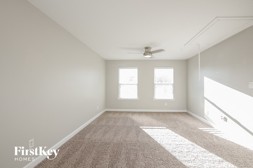 an empty room with a ceiling fan and two windows