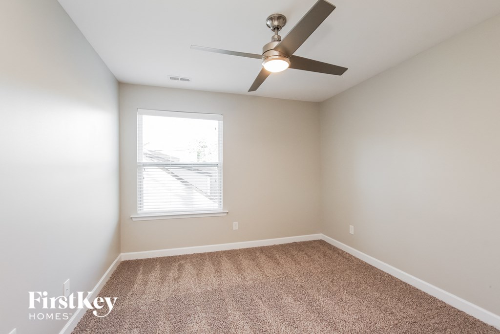 an empty room with a ceiling fan and a window