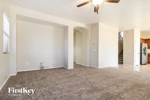 A spacious living room with a carpeted floor and a ceiling fan.