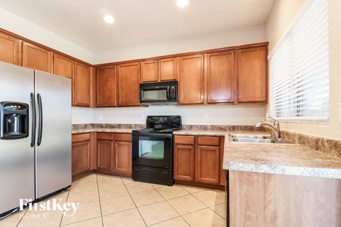 A kitchen with wooden cabinets and a stainless steel refrigerator.