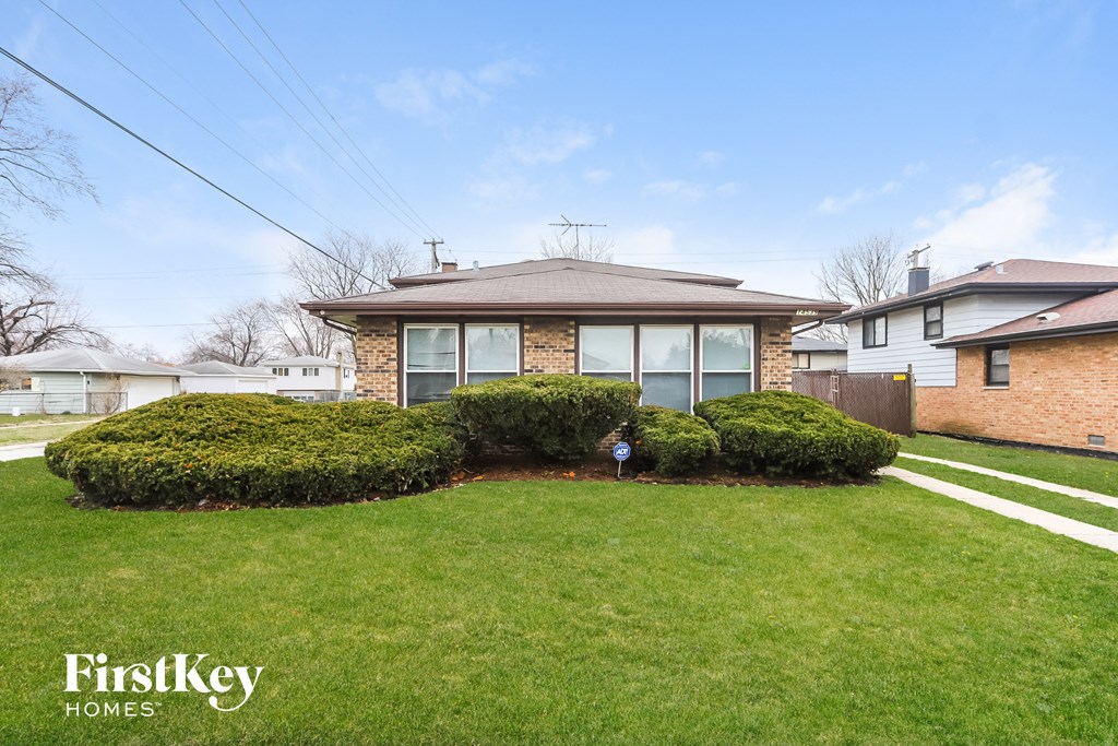 a brick house with a lawn and some bushes
