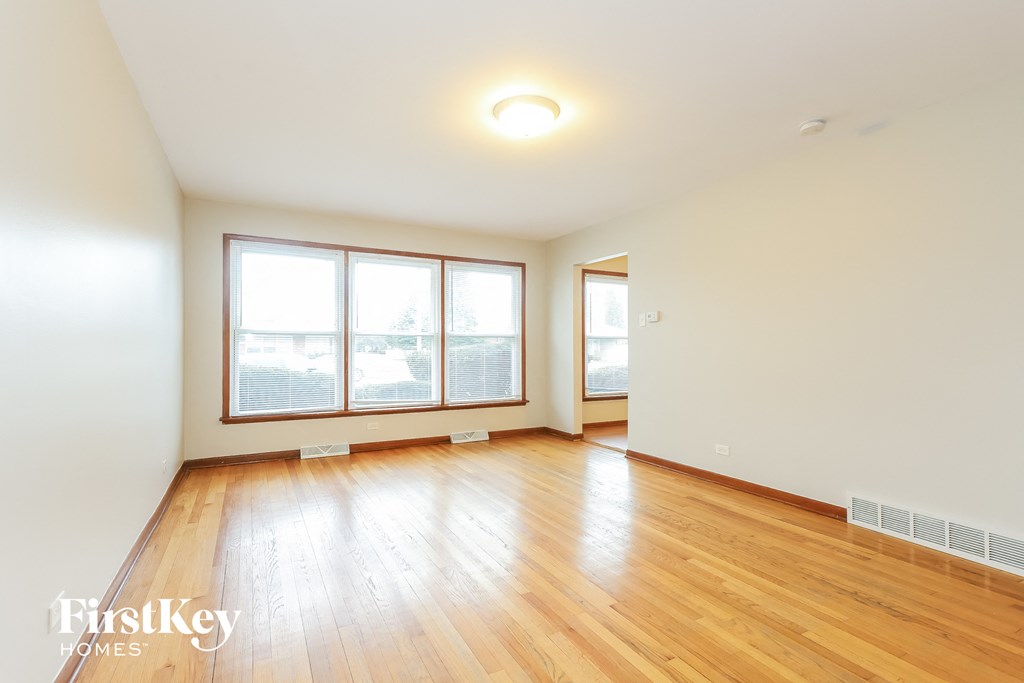an empty living room with wood floors and large windows