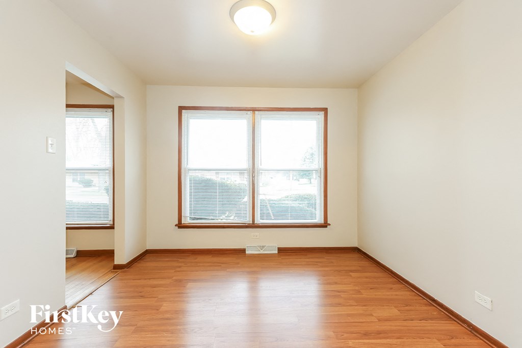 an empty living room with wood floors and two windows