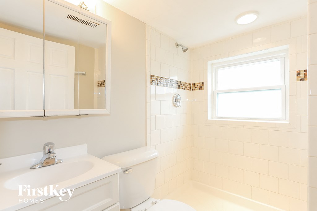 a white bathroom with a toilet sink and mirror and a window