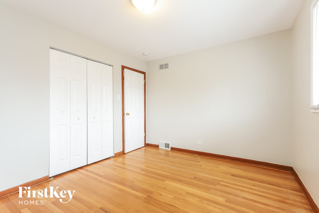 a bedroom with wood floors and white walls and two closets