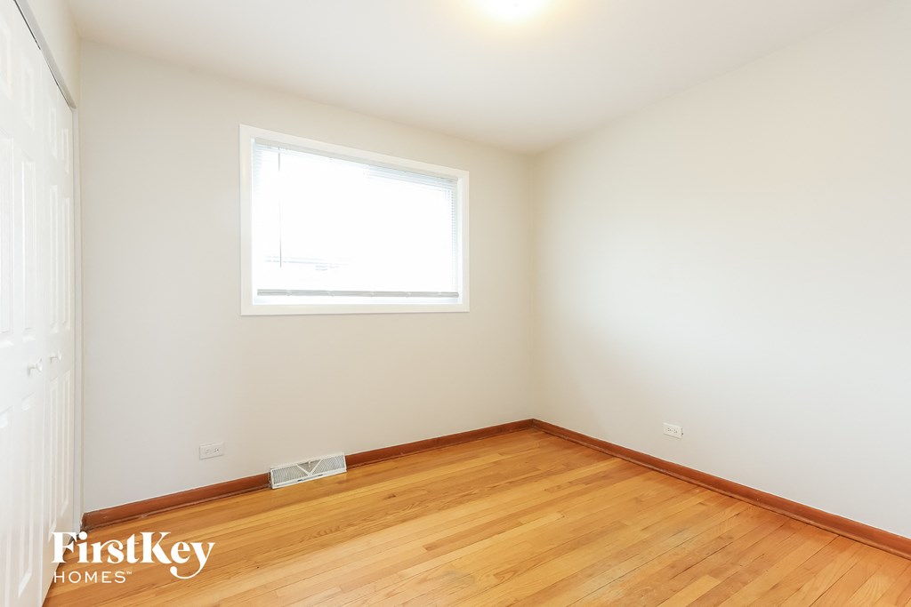 a bedroom with wood flooring and a window