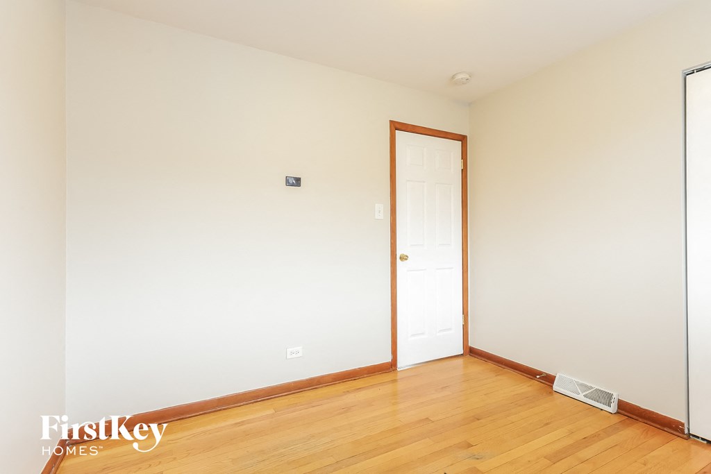 a bedroom with white walls and wood floors and a door