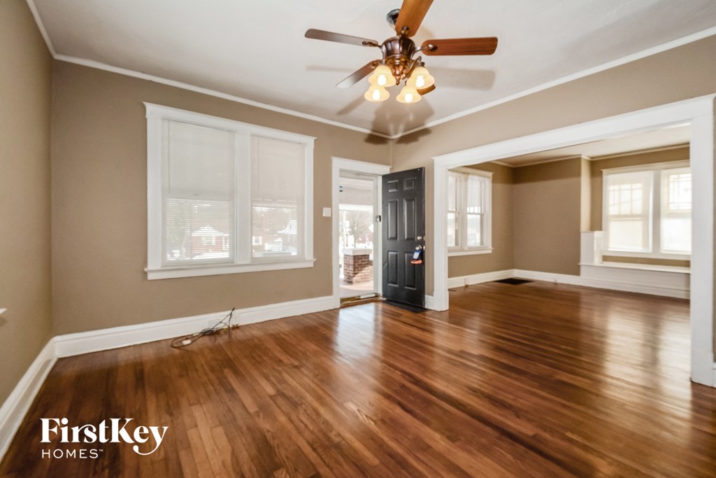 A spacious room with wooden floors and a ceiling fan.