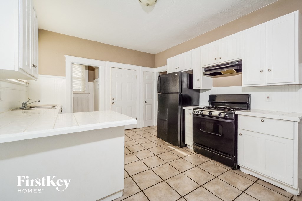 A kitchen with black appliances and white cabinets.