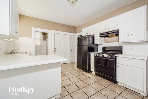 A kitchen with black appliances and white cabinets.