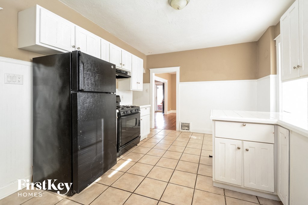 A kitchen with a black fridge and white cabinets.