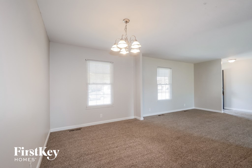 a spacious living room with carpet and a chandelier