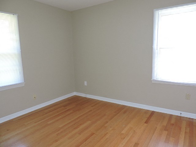 A room with wooden floors and two windows.