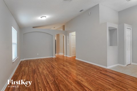 A spacious room with wooden flooring and white walls.