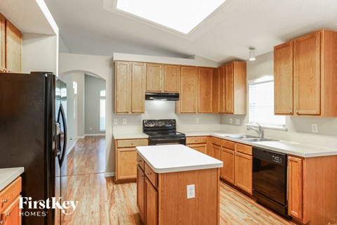 A kitchen with wooden cabinets and a black fridge.