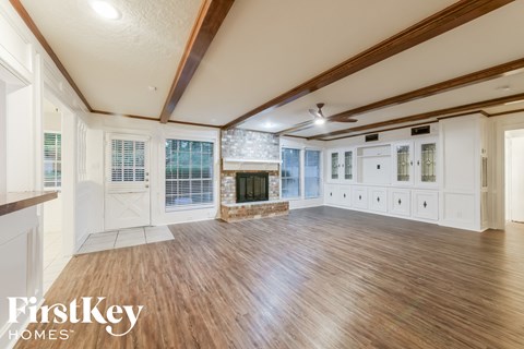 A spacious room with wooden floors and a fireplace.