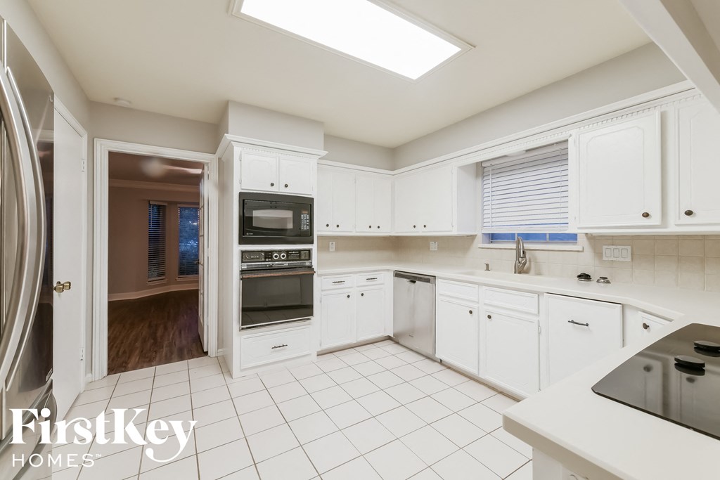 A kitchen with white cabinets and appliances, with a skylight above the countertop.