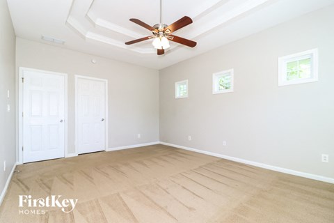 A spacious room with a ceiling fan and light, two doors, and a window.