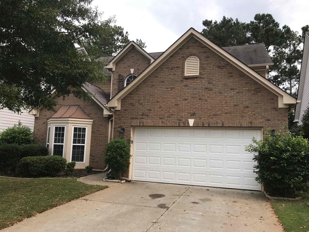 A house with a white garage door and a brown brick exterior.