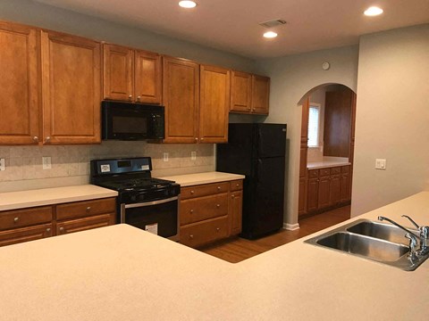 A kitchen with wooden cabinets and black appliances.