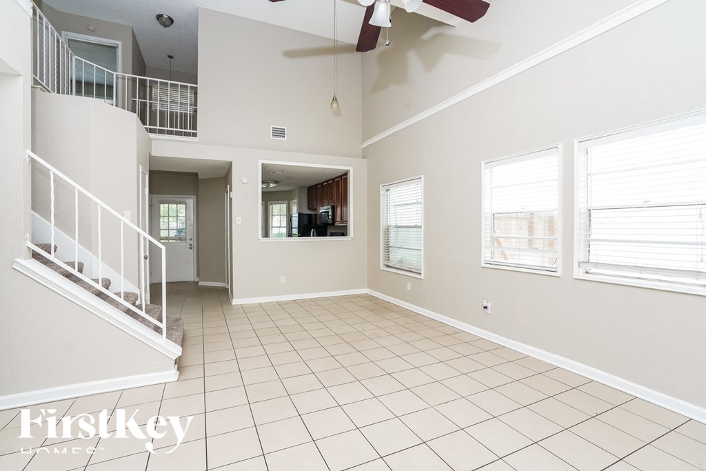 an empty living room with a staircase and a ceiling fan