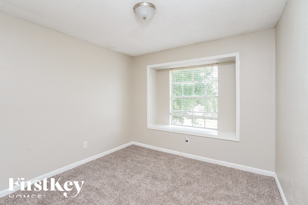 a bedroom with a window and carpeted floor