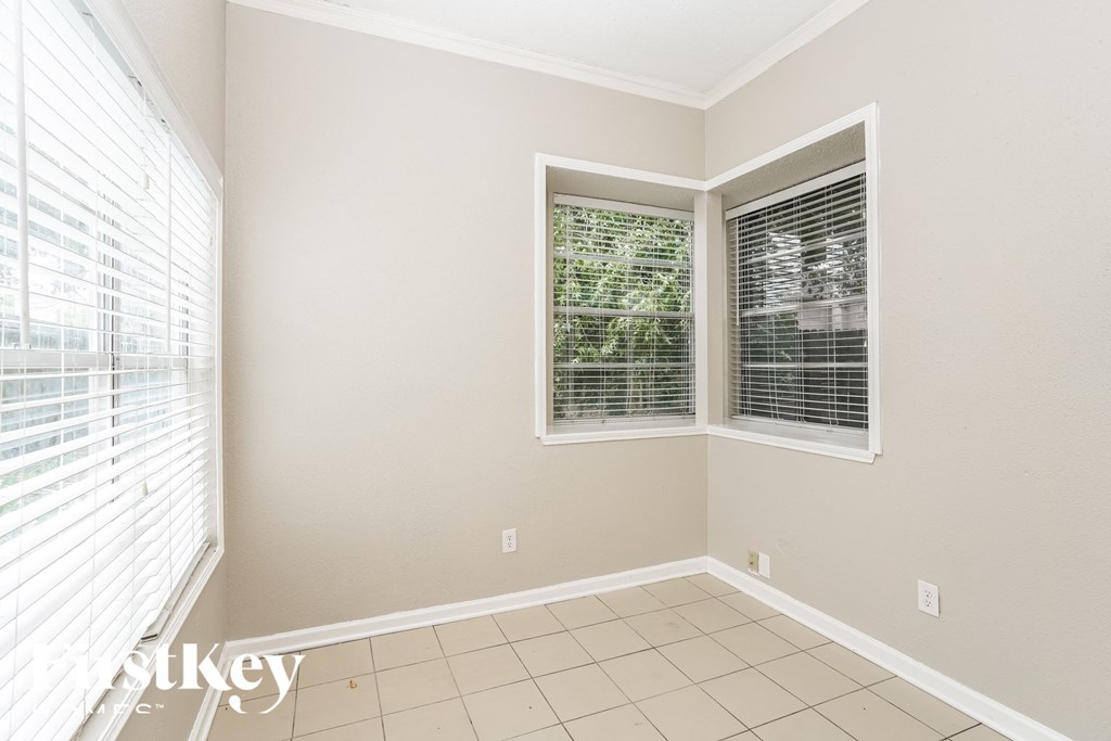 an empty living room with three windows and a tiled floor