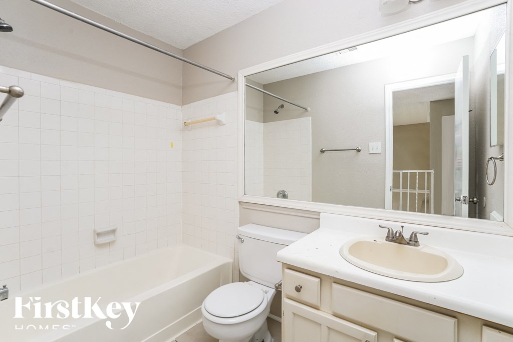 a white bathroom with a sink and a toilet and a mirror
