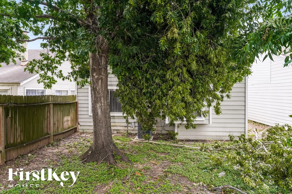 the backyard of a house with a tree and a fence