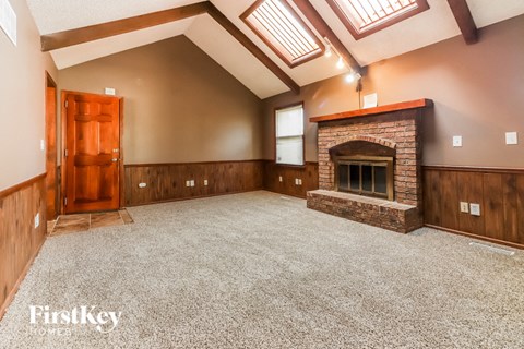 a large empty living room with a fireplace and a door