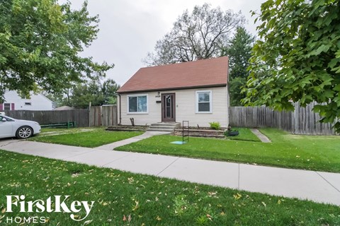 a small white house with a yard and a sidewalk