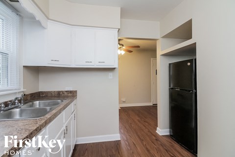 a kitchen with white cabinets and a black refrigerator