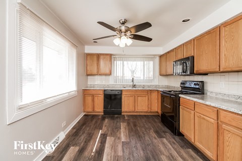 a kitchen with wooden cabinets and a ceiling fan