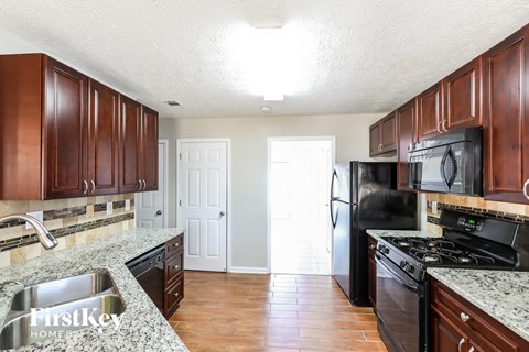 A kitchen with dark wood cabinets and a black refrigerator.