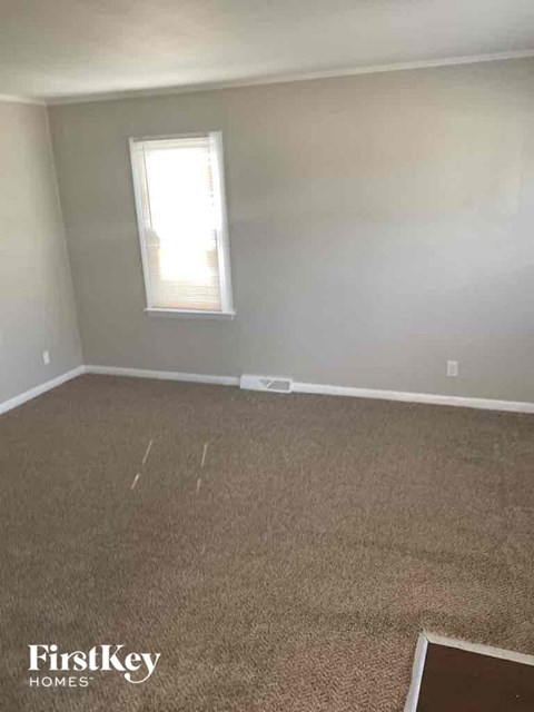 an empty room with a carpeted floor and a window