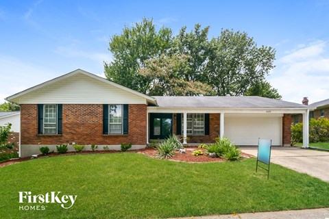 a small brick house with a lawn and a driveway