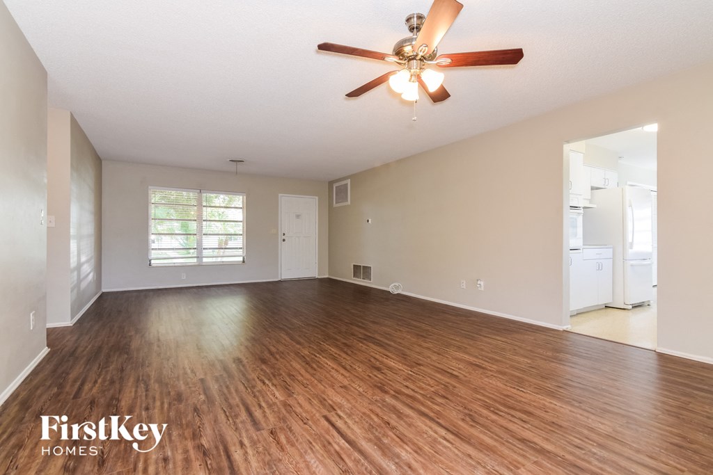 A spacious room with a ceiling fan and wooden flooring.